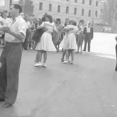 Radosne potańcówki w Warszawie. Młode pary tańczą na ulicy, otoczone przez widzów.