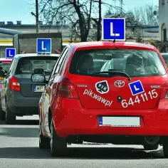 Czerwony samochód nauki jazdy z literą "L" na dachu. Zastanawiasz się, ile zarabia instruktor jazdy?