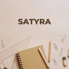 Szkolne przybory i napis "SATYRA" na jasnym tle. Może to być zapowiedź lekcji o literaturze, gdzie satyra odgrywa ważną rolę.