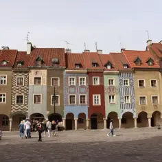 Kolorowe kamienice na Starym Rynku w Poznaniu. Co ciekawego w Poznaniu? Tętniący życiem plac, ludzie spacerujący pod arkadami.
