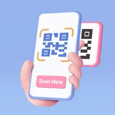 Dłoń trzyma smartfon z niebieskim kodem QR i przyciskiem "Scan Here". Obok drugi telefon z czarnym kodem. Darmowy skaner kodów QR.