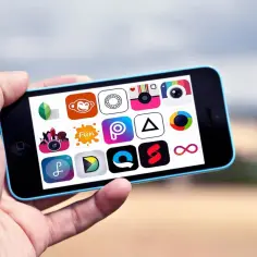 Ręka trzyma smartfon z ekranem pełnym ikon aplikacji do robienia zdjęć i edycji.