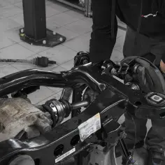 Mechanik pracuje nad demontażem półosi ze skrzyni biegów. W tle leży już jedna wyjęta półos.