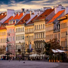 Kolorowe kamienice warszawskie oświetlone zachodzącym słońcem.