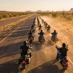 Konwój motocyklistów, przypominający Hells Angels Polska, przemierza pustynną drogę w Monument Valley.