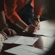 Dłoń podpisuje dokument, na którym widnieje klauzula RODO.