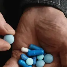 Dłoń trzyma niebieskie i białe tabletki. Czy Citaxin to psychotrop?