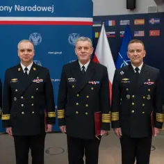 Pięciu oficerów w ciemnych mundurach marynarki wojennej, z odznaczeniami i złotymi paskami na rękawach, symbolizującymi wyższy stopień podoficerski w marynarce wojennej.