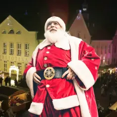 Święty Mikołaj na jarmarku bożonarodzeniowym w Olsztynie, w tle choinka i kolorowo oświetlone kamienice.