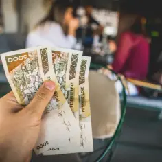 Dłoń trzyma banknoty 5000 leków. To jest jaka waluta w Albanii, idealna na wakacyjne zakupy.