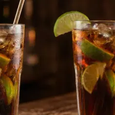 Dwa orzeźwiające rumy z colą, ozdobione kawałkami limonki, stoją na barze.