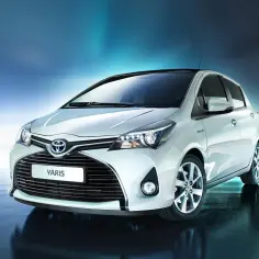Biały Toyota Yaris, znany też jako Vitz, prezentuje się elegancko na tle błękitnego gradientu.