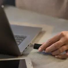 Dłoń wkłada pendrive do MacBooka. Prosty sposób, jak otworzyć pendrive na macbooku.