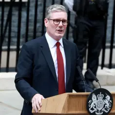 Keir Starmer, premier Wielkiej Brytanii, przemawia przy mównicy z herbem królewskim.
