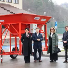 Cztery osoby stoją obok czerwonej maszyny, która może być używana do transportu kamionkowego materiału budowlanego.