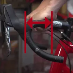 Dłonie ustawiają kierownicę roweru, pokazując jej szerokość. Dowiedz się, jak ustawić kierownicę w rowerze dla optymalnego komfortu.