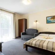 Przytulne pokoje w Jastrzębiej Górze. Wygodne łóżko, sofa i biurko czekają na gości w kwaterach prywatnych.