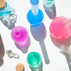 Kolorowe fiolki i butelki, niektóre z korkami, inne z pipetkami, jakby do tworzenia perfum lub eliksirów z phenoxyethanol.