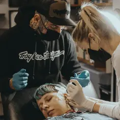 Na kursie piercingu mistrzowie w rękawiczkach wykonują zabieg. Uczą się, jak profesjonalnie przekłuwać uszy.
