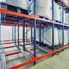 Wielki stos białych worków z materiałem na regałach magazynowych.
