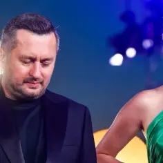 Mężczyzna w czarnym garniturze i kobieta w zielonej sukni. Czy zastanawiasz się, izabella krzan ile zarabia?