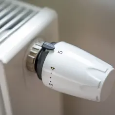 Biały termostat na grzejniku, ustawiony na 4. Dowiedz się, jak działa termostat w grzejniku, by oszczędzać energię.