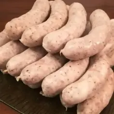 Stos białej kiełbasy, gotowej do przygotowania według przepisu na 5 kg. Idealna na rodzinne spotkania.