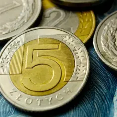 Monety 5 zł, 2 zł i 1 zł na tle banknotu. Obrazek symbolizuje zarobki, w tym średnią płacę w Polsce.