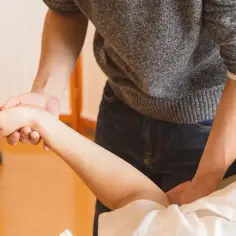 Fizjoterapeuta delikatnie uciska nadgarstek pacjenta, przypominając o tym, czego nie wolno po operacji cieśni nadgarstka.