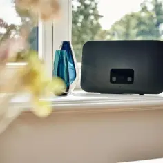 Nowoczesna antena do internetu mobilnego, elegancko ustawiona na parapecie obok ozdobnych wazonów.