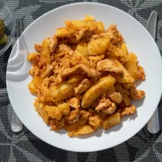 Pyszne danie z kurczakiem i ziemniakami, przypominające smaki kuchni węgierskiej. Obok miseczka ogórków kiszonych.