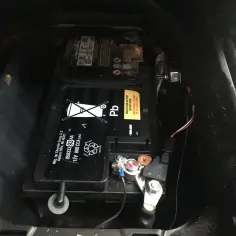 Akumulator w Jeep Grand Cherokee WK2 znajduje się w bagażniku, pod podłogą. Widoczny jest czarny akumulator z oznaczeniem "Pb".