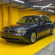Elegancki, granatowy sedan BMW E67 lśni w garażu o żółtych ścianach.