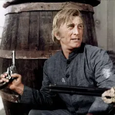 Kirk Douglas w westernowym filmie, z rewolwerem w dłoni, gotów do akcji.
