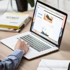 Mężczyzna w kratę pracuje na laptopie, pijąc kawę. To jego ulga na start dnia, by wszystko sprawnie ogarnąć.