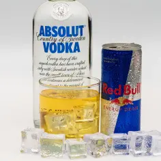 Butelka wódki Absolut, szklanka z drinkiem i puszka Red Bulla. Idealny drink z energetykiem na upalne dni.