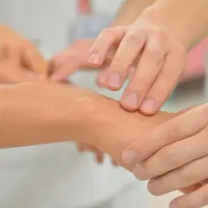 Dłonie badają nadgarstek, szukając oznak wewnętrznego niepokoju i drżenia.