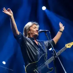 Chris Norman na scenie, z rękami w górze. Jego żona, która jest jego wielką fanką, pewnie jest dumna.