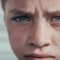 Zamyślony chłopiec z niebieskimi oczami, zmartwiony wyraz twarzy. To mogą być objawy parentyfikacji, gdy dziecko przejmuje role dorosłych.