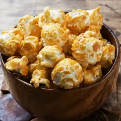 Chrupiący karmelowy popcorn w drewnianej misce. Idealny, gdy zastanawiasz się, jak zrobić popcorn na wieczór filmowy.