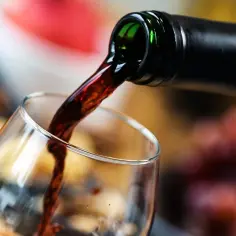 Ciemne wino leje się z butelki do kieliszka. Poznaj przyczyny mętności wina domowego i jak wyklarować napój.