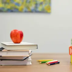 Stos książek z jabłkiem, kredki i klocki ABC. Nawet po 18 roku życia nauczanie domowe może być inspirujące.