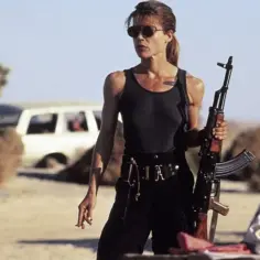 Linda Hamilton w roli Sary Connor, gotowa do walki w pustynnym krajobrazie. Jej filmy i seriale to ikony kina akcji.
