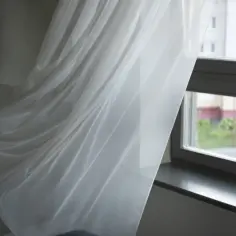 Białe firanki falujące przy oknie. Dowiedz się, jak doprać pożółkłe firanki domowym sposobem, żeby były śnieżnobiałe.