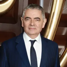 Rowan Atkinson, znany z roli Jasia Fasoli, w eleganckim garniturze.