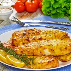 Pieczona pierś z kurczaka w sosie musztardowym, podana z cytryną i ziołami. Pyszne danie w naczyniu.