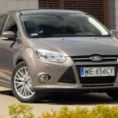 Brązowy Ford Focus MK3 na tle nowoczesnego budynku. Wiele osób szuka ford focus mk3 opinie, ten model jest świetnym wyborem.