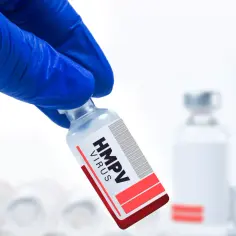 Rękawiczka w niebieskiej rękawicy trzyma fiolkę z napisem "HMPV VIRUS". Czy to nowy wirus w Chinach?