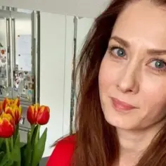 Anita Sokołowska wiek. Uśmiechnięta kobieta z rudymi włosami, w tle bukiet tulipanów i lustrzane szafki.