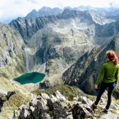 Dziewczyna na szczycie w Tatrach Wysokich 2494 m podziwia widok na turkusowe jezioro i skaliste pasma górskie.